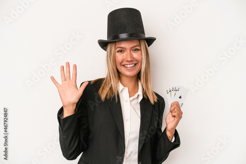 Young caucasian wizard woman holding magic card isolated on white background smiling cheerful showing number five with fingers.