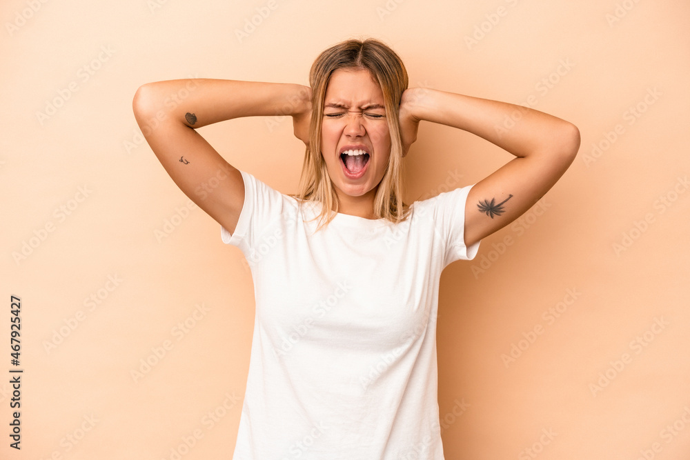 Young caucasian woman isolated on beige background covering ears with hands trying not to hear too loud sound. Young caucasian woman isolated on beige background covering ears with hands trying not to hear too loud sound.