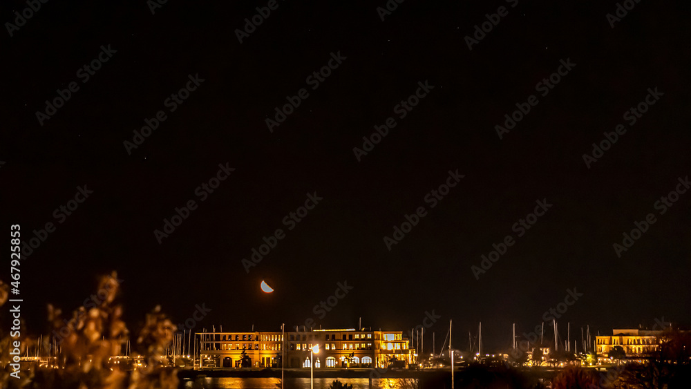 Mond geht am Abend über dem Hafen von Rostock Warnemünde auf