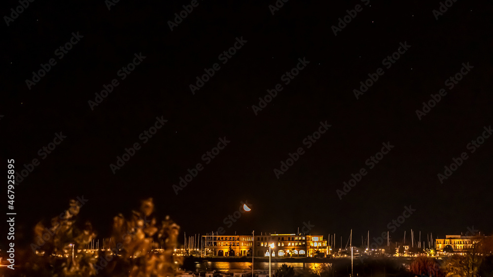 Mond geht am Abend über dem Hafen von Rostock Warnemünde auf