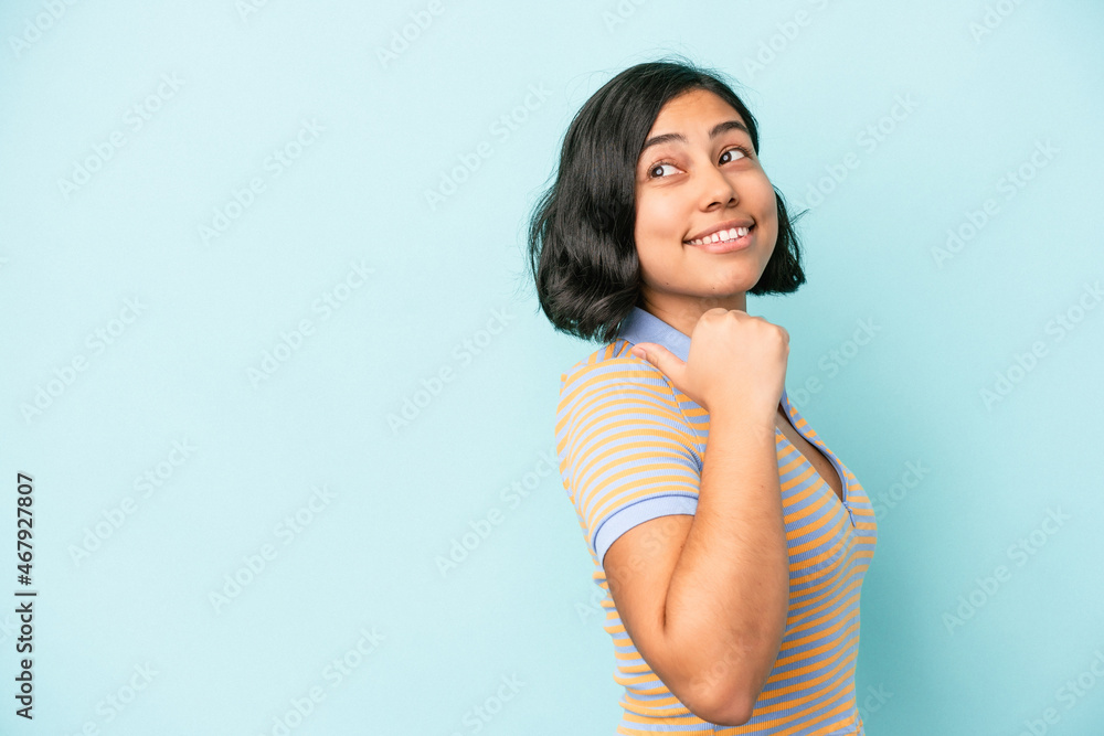 Young latin woman isolated on blue background points with thumb finger away, laughing and carefree. Young latin woman isolated on blue background points with thumb finger away, laughing and carefree.