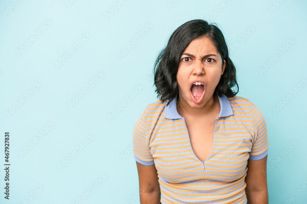 Young latin woman isolated on blue background shouting very angry, rage concept, frustrated. Young latin woman isolated on blue background shouting very angry, rage concept, frustrated.