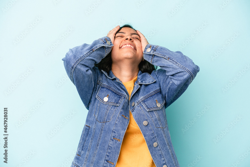 Young latin woman isolated on blue background laughs joyfully keeping hands on head. Happiness concept. Young latin woman isolated on blue background laughs joyfully keeping hands on head. Happiness concept.