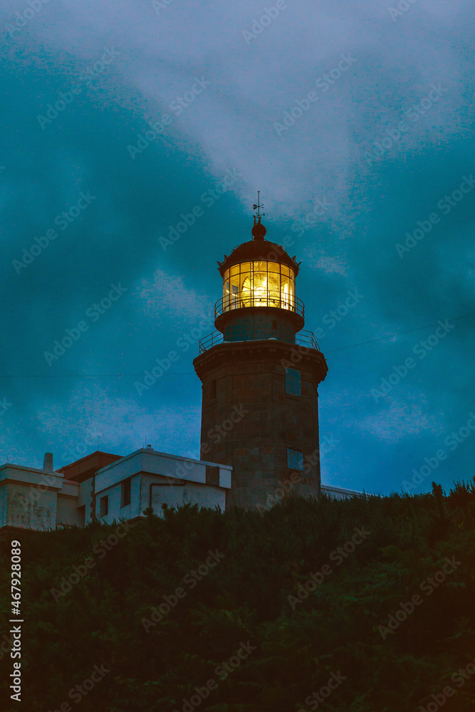 Horizontal view of a lighthouse at night with the light on. Panoramic view of spanish lighthouse in the coast of vasque country. Travel concept.