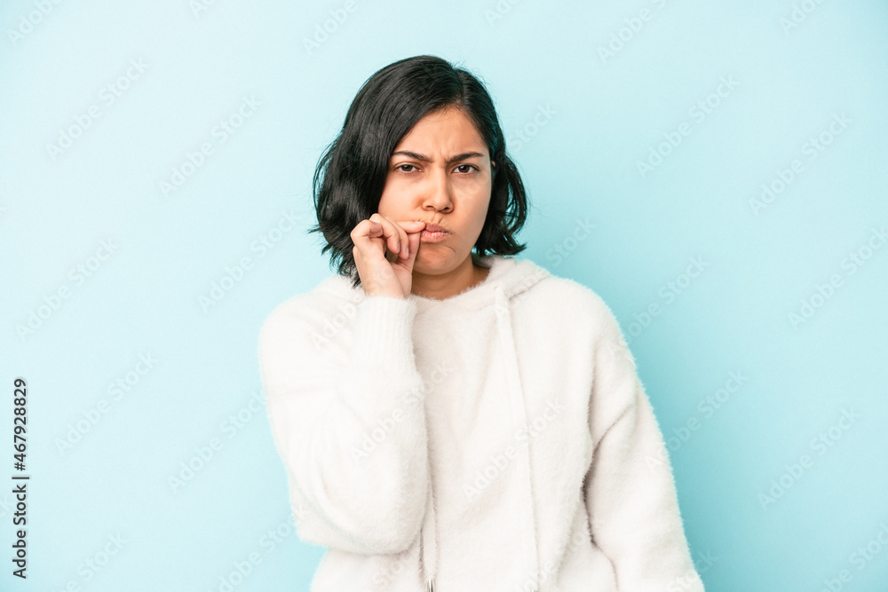 Young latin woman isolated on blue background with fingers on lips keeping a secret. Young latin woman isolated on blue background with fingers on lips keeping a secret.