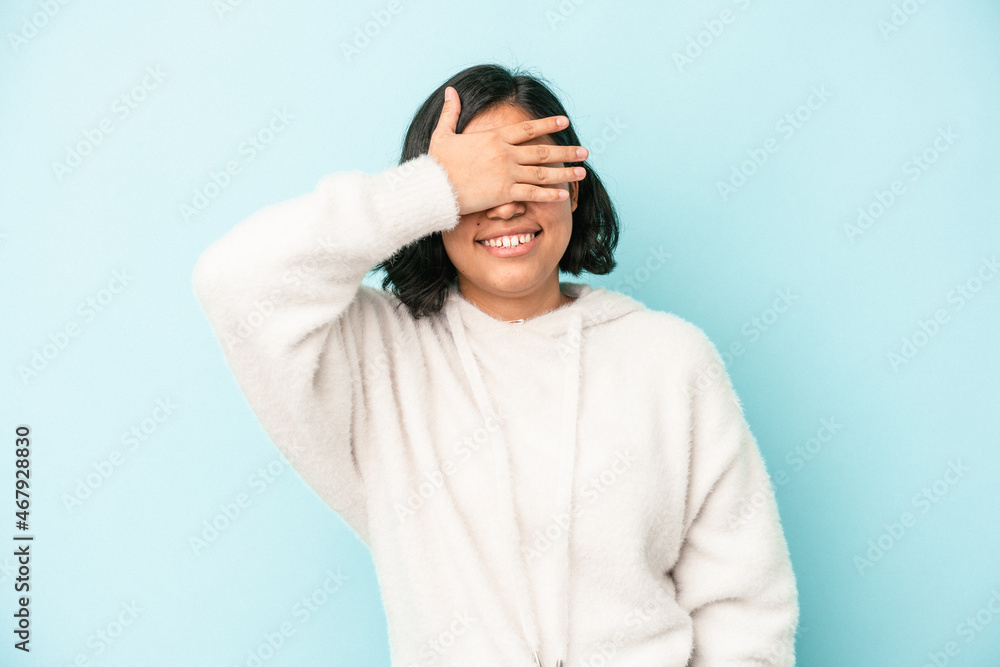 Young latin woman isolated on blue background covers eyes with hands, smiles broadly waiting for a surprise. Young latin woman isolated on blue background covers eyes with hands, smiles broadly waiting for a surprise.