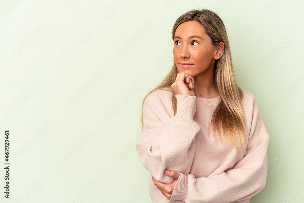 Young caucasian woman isolated on green background looking sideways with doubtful and skeptical expression. Young caucasian woman isolated on green background looking sideways with doubtful and skeptical expression.