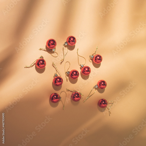 Top view of tropical leaf shadow and red Christmas baubles on sand color background. Trendy flat lay. Minimal New Year party concept. Vintage aesthetic.