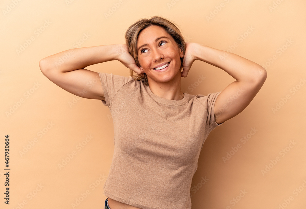 Young caucasian woman isolated on beige background stretching arms, relaxed position. Young caucasian woman isolated on beige background stretching arms, relaxed position.