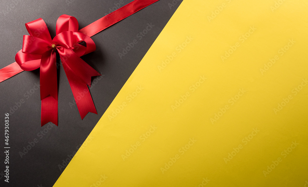 Top view of red ribbon decoration on black and yellow background. Shopping concept boxing day and Black Friday composition. Top view of red ribbon decoration on black and yellow background. Shopping concept boxing day and Black Friday composition.