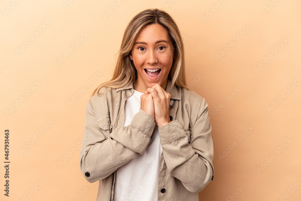 Young caucasian woman isolated on beige background praying for luck, amazed and opening mouth looking to front. Young caucasian woman isolated on beige background praying for luck, amazed and opening mouth looking to front.