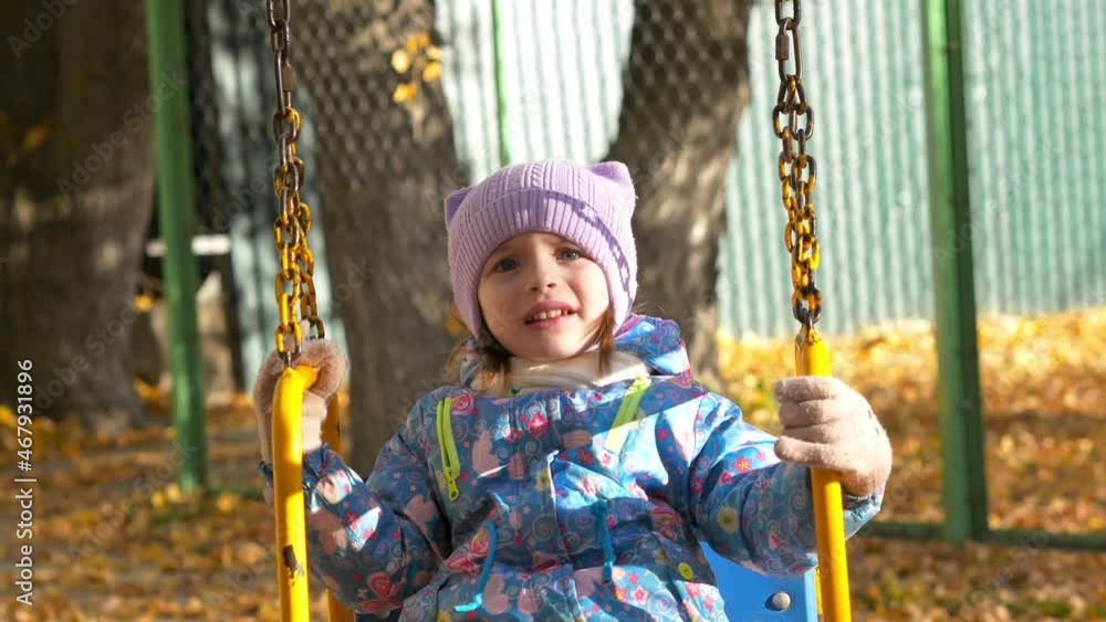 Autumn, a child on a playground on a swing is naughty and shaking his head. A 3-year-old girl is upset and naughty. Children's whims, tantrums Autumn, a child on a playground on a swing is naughty and shaking his head. A 3-year-old girl is upset and naughty. Children's whims, tantrums