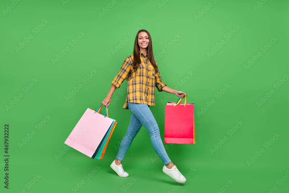 Full size profile portrait of cheerful positive girl hold packages walking isolated on green color background