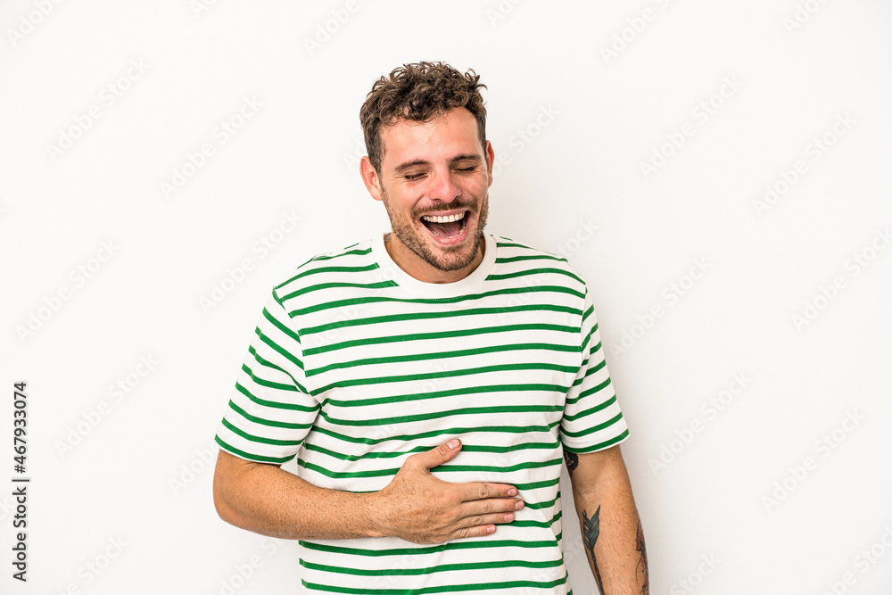 Fototapeta premium Young caucasian man isolated on white background touches tummy, smiles gently, eating and satisfaction concept.