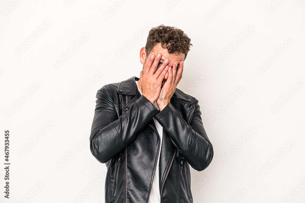 Young caucasian man isolated on white background blink at the camera through fingers, embarrassed covering face. Young caucasian man isolated on white background blink at the camera through fingers, embarrassed covering face.