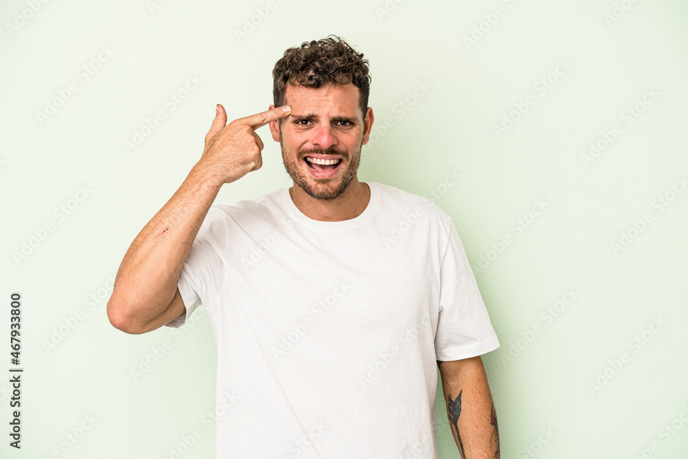 Young caucasian man isolated on green background showing a disappointment gesture with forefinger. Young caucasian man isolated on green background showing a disappointment gesture with forefinger.