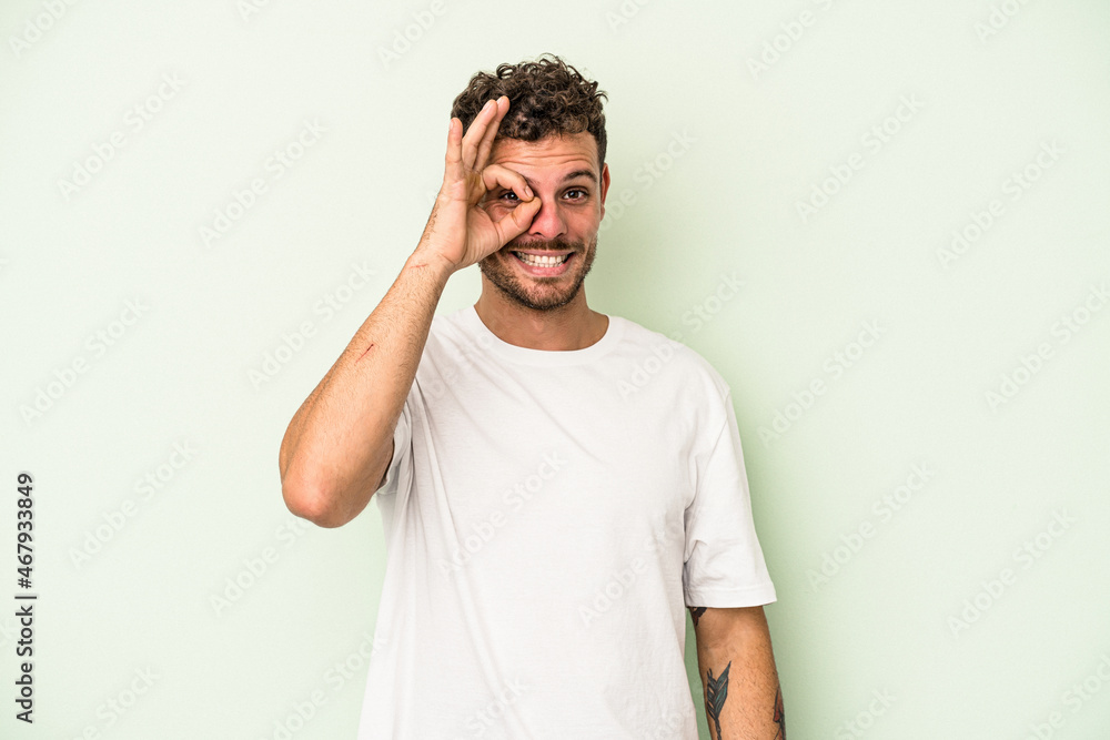 Young caucasian man isolated on green background excited keeping ok gesture on eye. Young caucasian man isolated on green background excited keeping ok gesture on eye.