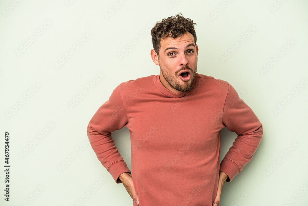 Young caucasian man isolated on green background being shocked because of something she has seen. Young caucasian man isolated on green background being shocked because of something she has seen.