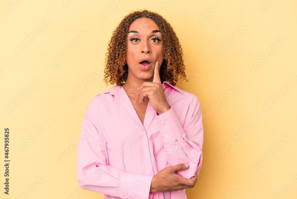 Young latin transsexual woman isolated on yellow background having some great idea, concept of creativity.