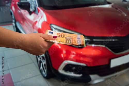 well-groomed female hands with manicure holding a round sum of euro in a car showroom. © RomanR