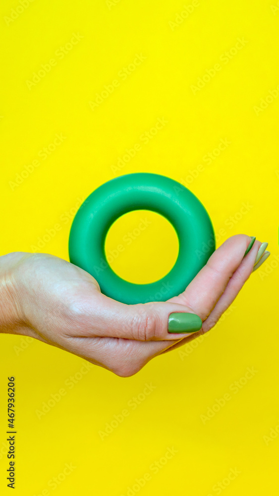 the green expander lies in the girl's palm. hand trainer in the hand of a woman. round coach. vertical image the green expander lies in the girl's palm. hand trainer in the hand of a woman. round coach. vertical image