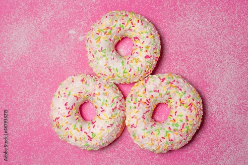 Three donuts on pink background.