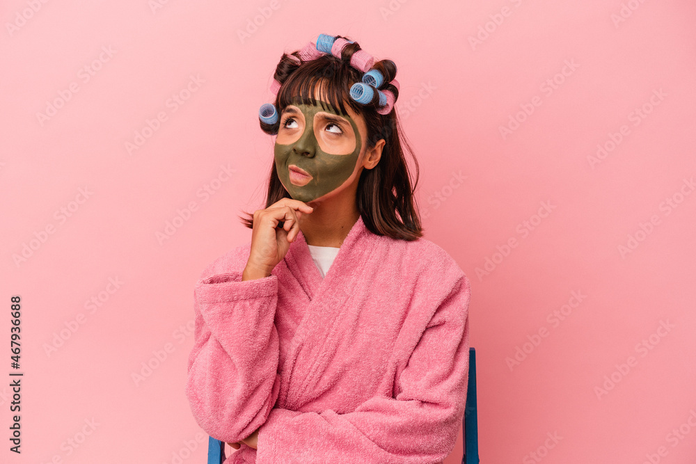 Young mixed race woman getting pretty in a house isolated on pink background looking sideways with doubtful and skeptical expression. Young mixed race woman getting pretty in a house isolated on pink background looking sideways with doubtful and skeptical expression.