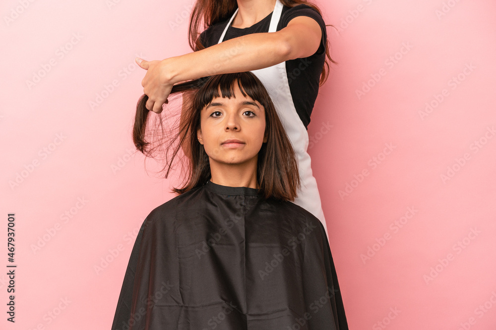 Young mixed race woman getting a haircut at the hairdresser isolated on pink background Young mixed race woman getting a haircut at the hairdresser isolated on pink background