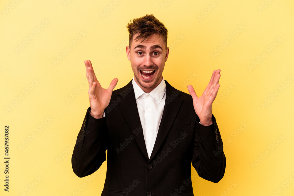 Young caucasian business man isolated on yellow background receiving a pleasant surprise, excited and raising hands. Young caucasian business man isolated on yellow background receiving a pleasant surprise, excited and raising hands.