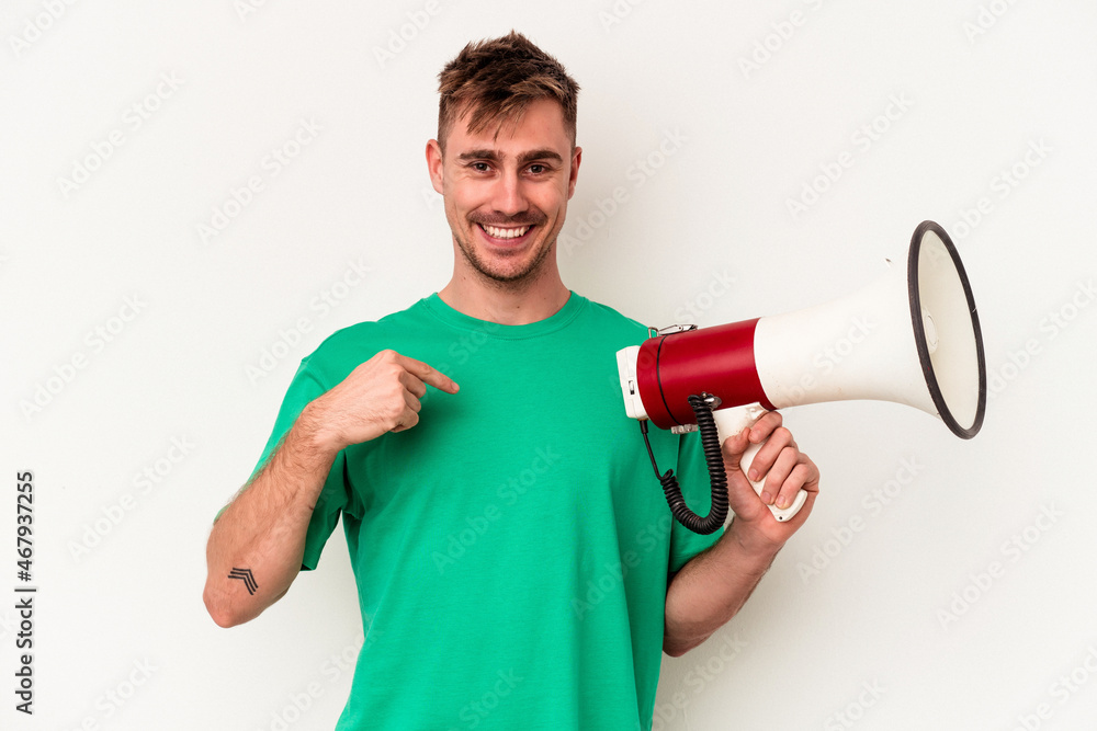 Young caucasian man holding megaphone isolated on white background person pointing by hand to a shirt copy space, proud and confident Young caucasian man holding megaphone isolated on white background person pointing by hand to a shirt copy space, proud and confident