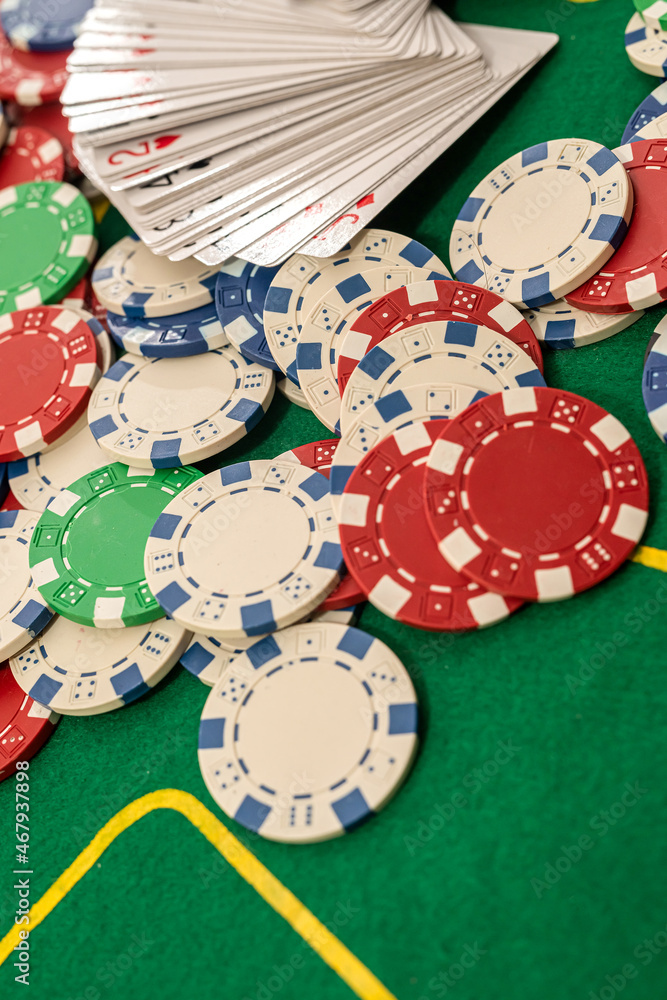 a deck of cards laid out in a fan with colored chips on a green professional poker table.