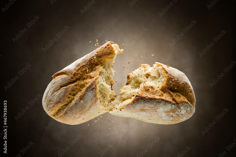 Fresh crunchy baked bread opened on brown background.