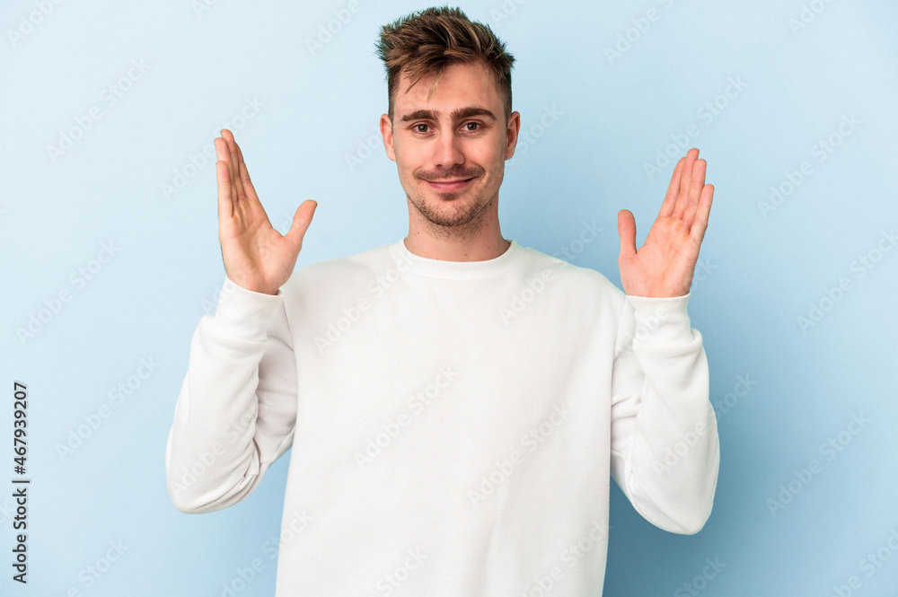 Young caucasian man isolated on blue background holding something little with forefingers, smiling and confident. Young caucasian man isolated on blue background holding something little with forefingers, smiling and confident.