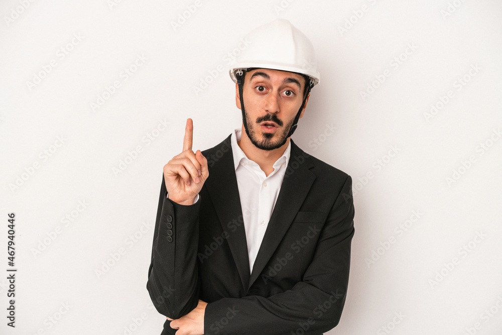 Young architect man wearing a construction helmet isolated on white background having some great idea, concept of creativity. Young architect man wearing a construction helmet isolated on white background having some great idea, concept of creativity.