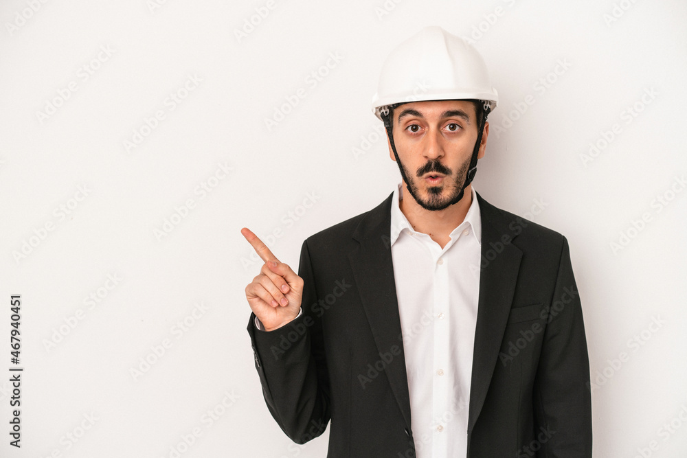 Young architect man wearing a construction helmet isolated on white background pointing to the side Young architect man wearing a construction helmet isolated on white background pointing to the side