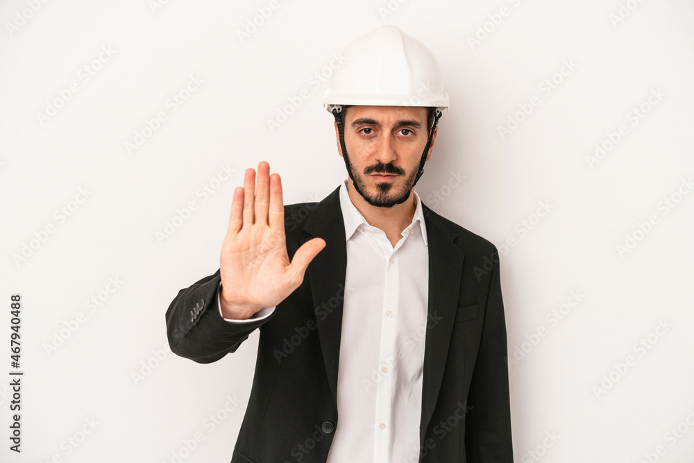 Young architect man wearing a construction helmet isolated on white background standing with outstretched hand showing stop sign, preventing you.