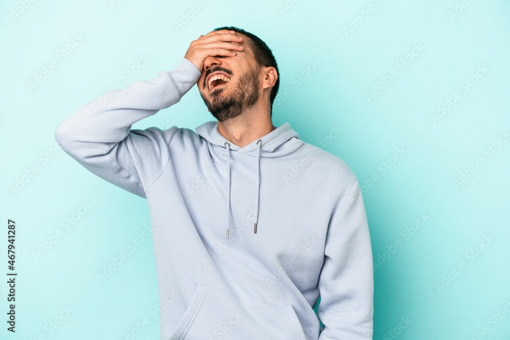 Young caucasian man isolated on blue background laughs joyfully keeping hands on head. Happiness concept. Young caucasian man isolated on blue background laughs joyfully keeping hands on head. Happiness concept.
