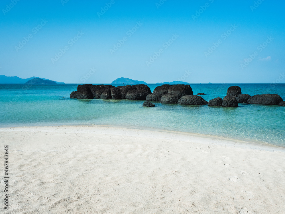 Peaceful white sand beach with iconic black volcanic rock of Koh Kham Island and crystal clear turquoise water. Near Koh Mak Island, Trat Province, Thailand. Peaceful white sand beach with iconic black volcanic rock of Koh Kham Island and crystal clear turquoise water. Near Koh Mak Island, Trat Province, Thailand.