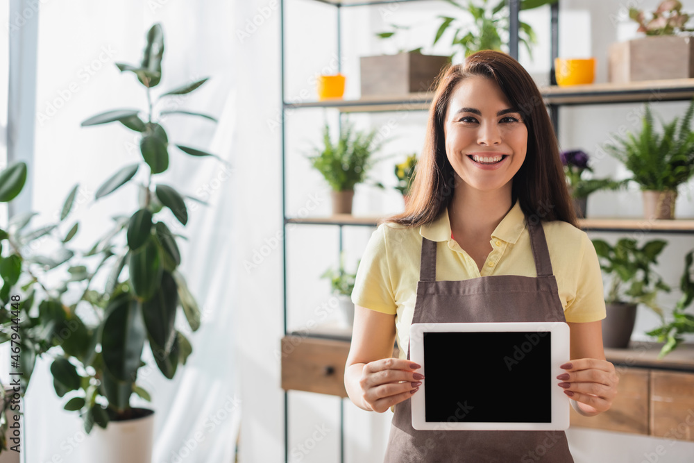Positive florist holding digital tablet in flower shop Positive florist holding digital tablet in flower shop