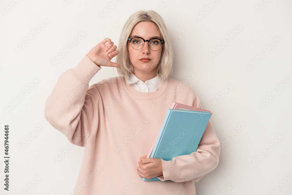 Young caucasian student woman holding books isolated on white background showing a dislike gesture, thumbs down. Disagreement concept.