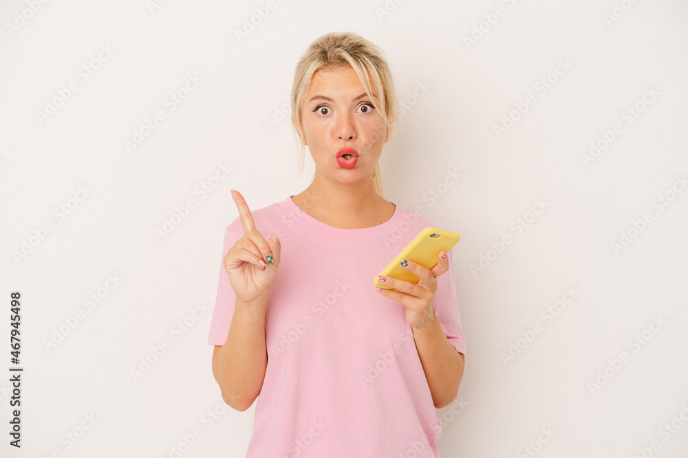 Young Russian woman holding mobile phone isolated on white background having some great idea, concept of creativity.