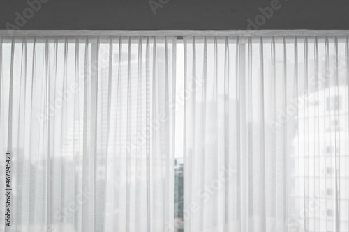 Beautiful translucent white fabric curtains in ripples with soft natural sunlight and see-through curtain balcony interior decorated the modern living room.