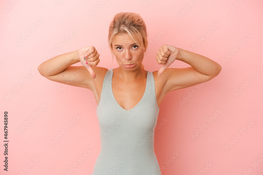 Young Russian woman isolated on pink background showing a dislike gesture, thumbs down. Disagreement concept. Young Russian woman isolated on pink background showing a dislike gesture, thumbs down. Disagreement concept.