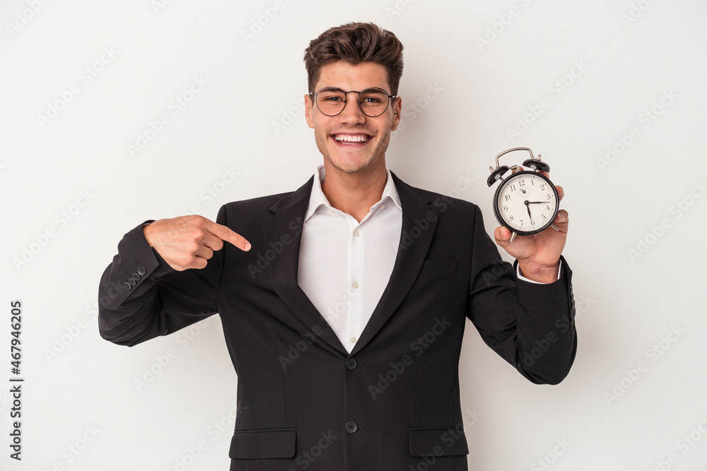 Young business caucasian man holding alarm clock isolated on white background person pointing by hand to a shirt copy space, proud and confident Young business caucasian man holding alarm clock isolated on white background person pointing by hand to a shirt copy space, proud and confident
