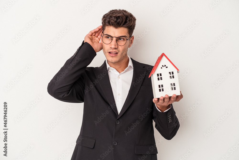 Young real estate caucasian agent isolated on white background trying to listening a gossip. Young real estate caucasian agent isolated on white background trying to listening a gossip.