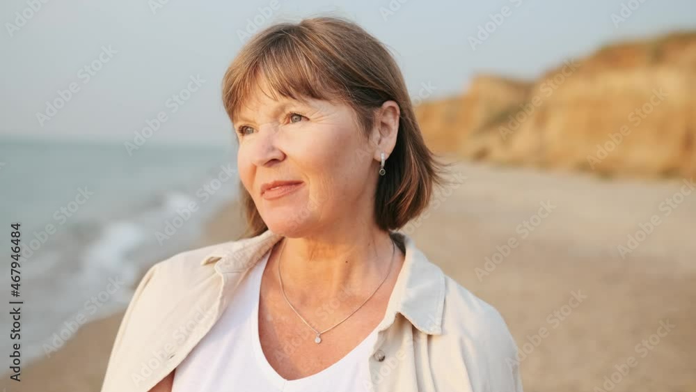 Concentrated mature woman looking at the sea on the beach Concentrated mature woman looking at the sea on the beach