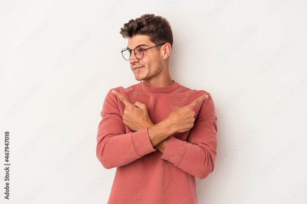 Young caucasian man isolated on white background points sideways, is trying to choose between two options. Young caucasian man isolated on white background points sideways, is trying to choose between two options.