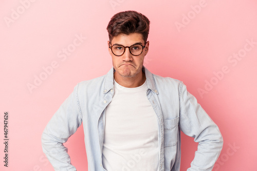 Young caucasian man isolated on pink background sad, serious face, feeling miserable and displeased.