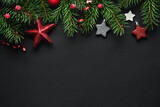 Black Christmas background with Christmas tree branches and red berries, winter festive composition with copy space. Top view.