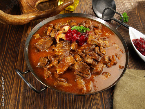 Fine Meat - Wild Game Meat Goulash in a Pan with Cranberries on wooden Background